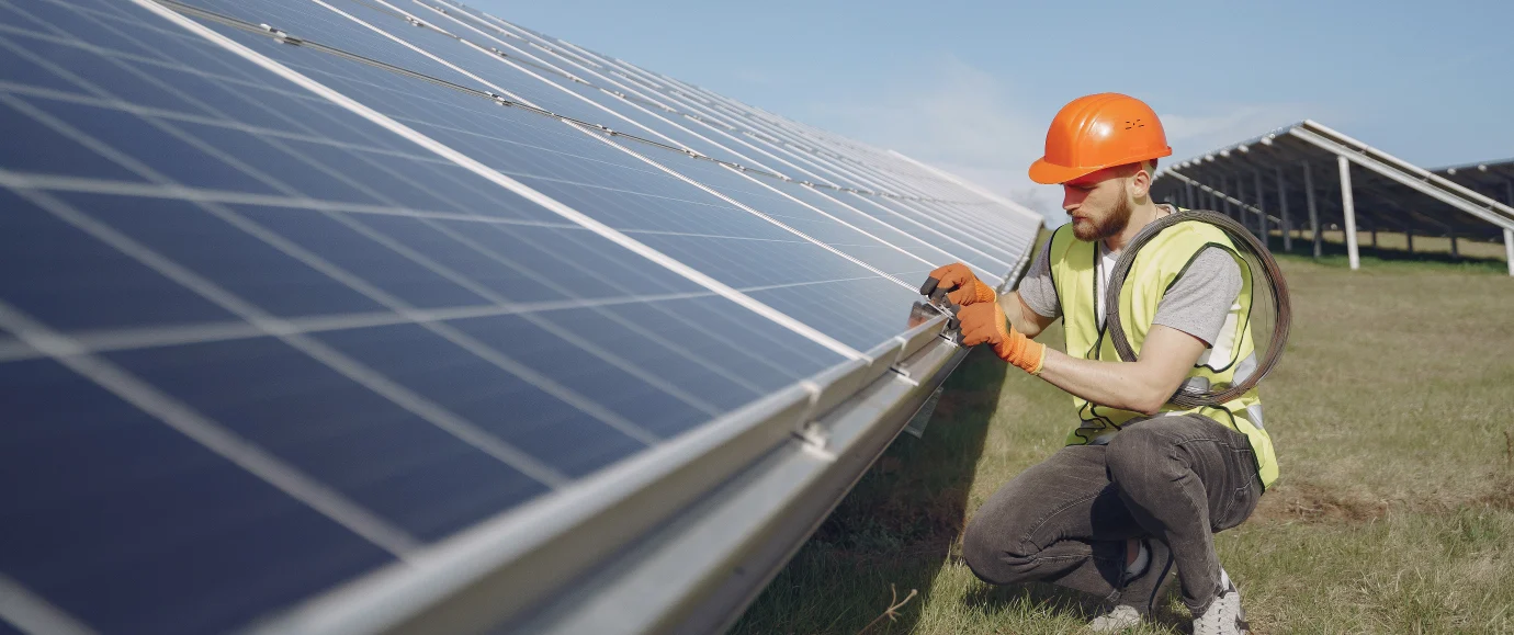 man in PPE inspecting a solar panel